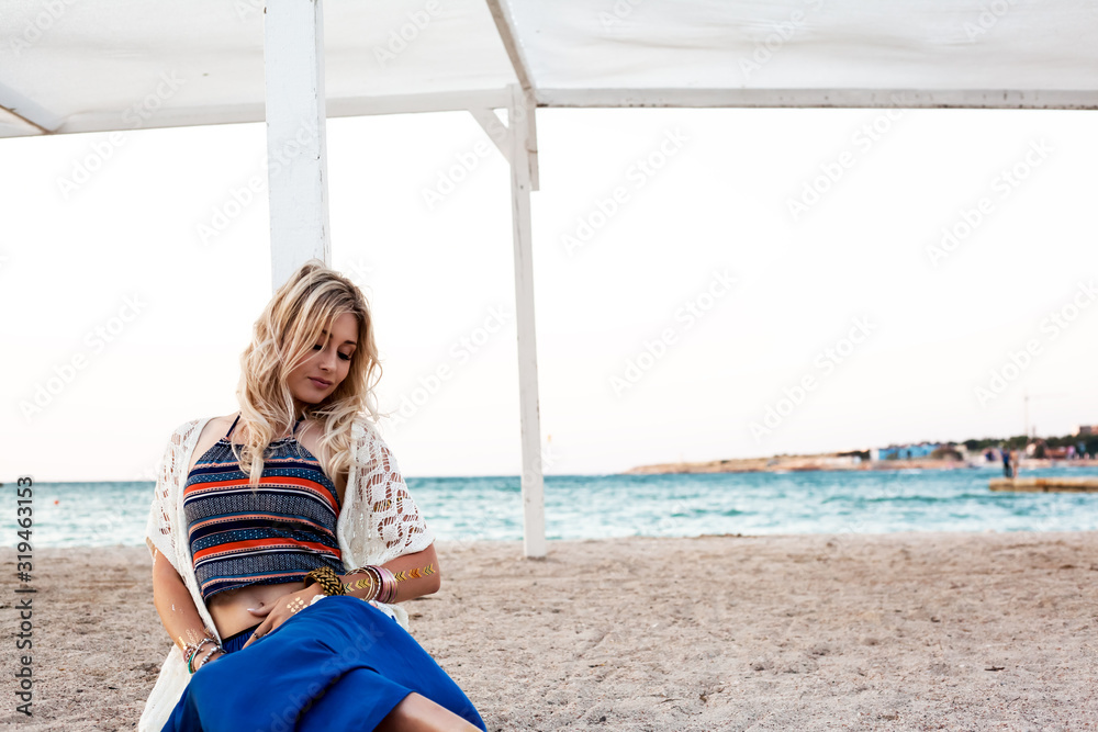 young beautiful woman wearing boho style clothes sit in the beach at summer day
