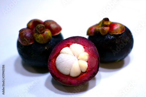 Fresh ripe mangosteen fruits on white table. Cross section showing the thick purple skin and white flesh