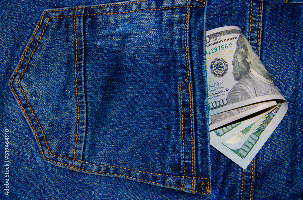 American banknotes in jeans pocket. A note in denominations of $ 100 peeps, stick out from the back, the foremost pants pocket. Money falls out of pocket. Flare effect. View from different angles American banknotes in jeans pocket. A note in denominations of $ 100 peeps, stick out from the back, the foremost pants pocket. Money falls out of pocket. Flare effect. View from different angles