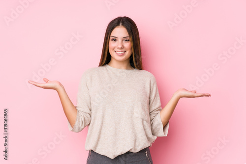 Young caucasian woman posing isolated makes scale with arms, feels happy and confident. photo