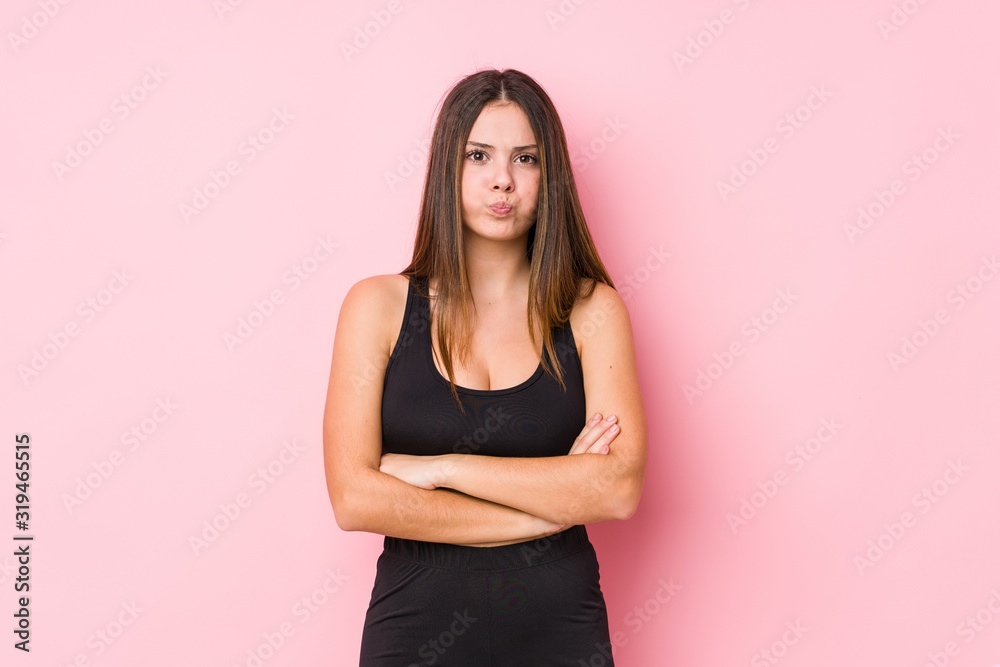 Young fitness caucasian woman isolated blows cheeks, has tired expression. Facial expression concept.