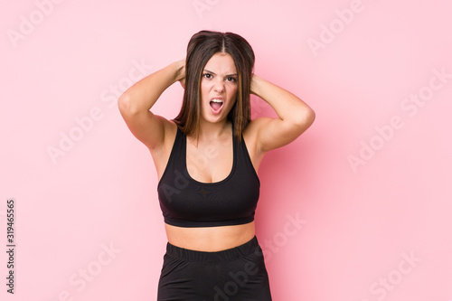 Young fitness caucasian woman isolated covering ears with hands trying not to hear too loud sound.