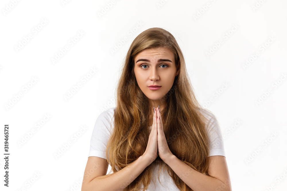 Portrait of young beautiful woman in t-shirt praying with pray gesture on white background Portrait of young beautiful woman in t-shirt praying with pray gesture on white background