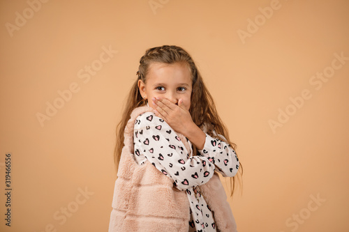 beautiful little girl asking to be quiet. child closes her mouth with her hand