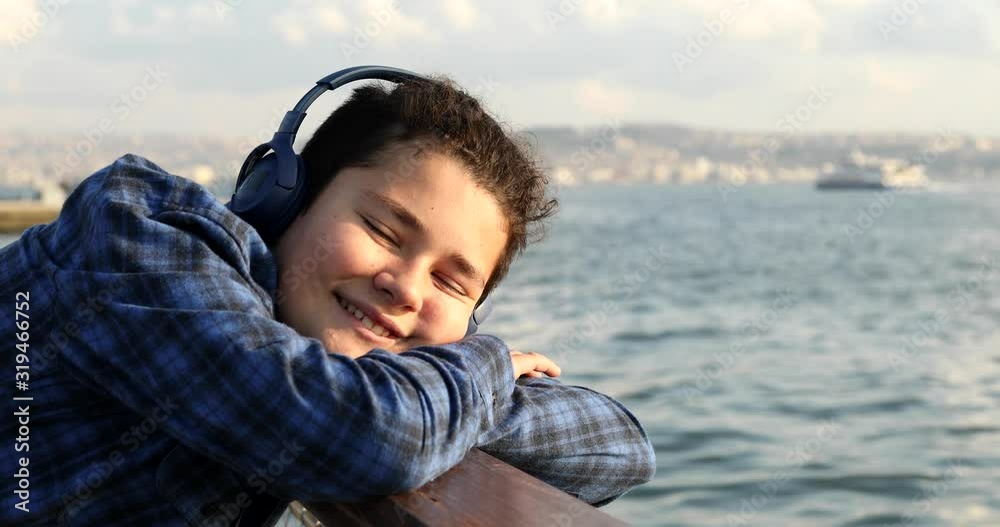 Portrait Of A Happy Teenage Boy With Headphone Looking To Camera And Smiling At The Seaside Portrait Of A Happy Teenage Boy With Headphone Looking To Camera And Smiling At The Seaside