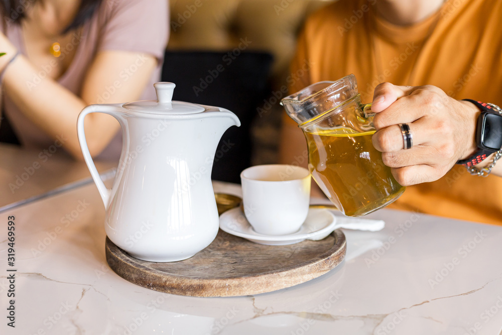 Hand pour tea in to cup of tea on the table. Hand pour tea in to cup of tea on the table.