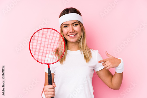 Young woman playing badminton isolated person pointing by hand to a shirt copy space, proud and confident © Asier