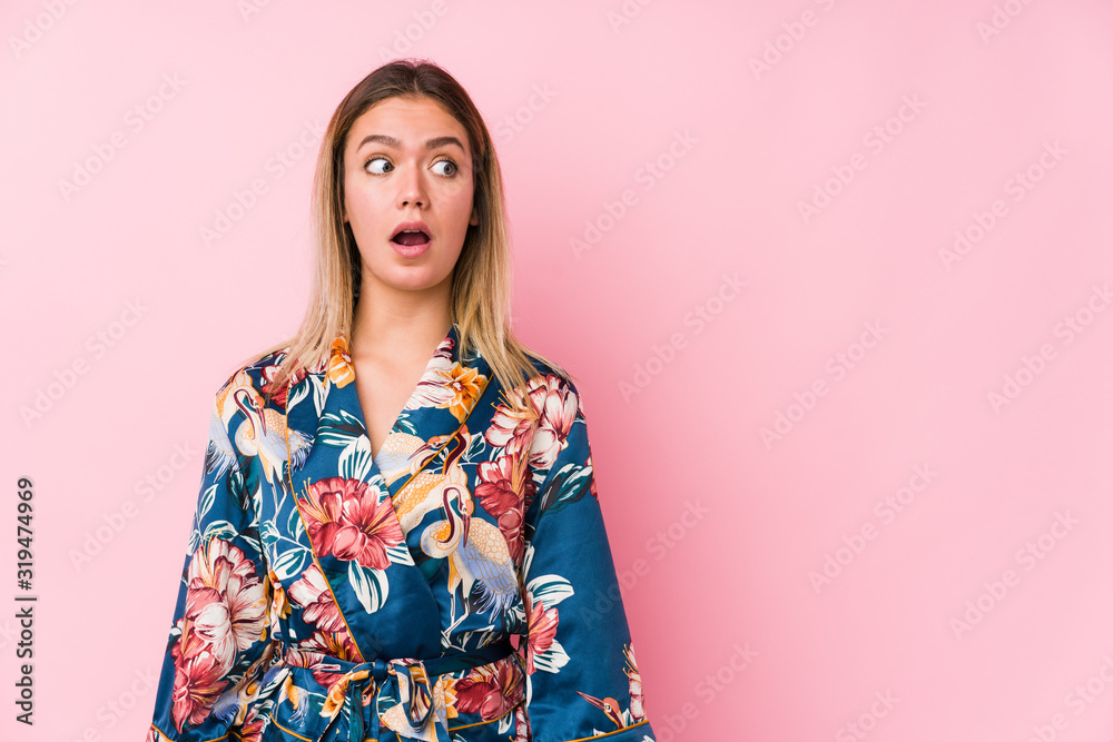 Young caucasian woman wearing pajamas being shocked because of something she has seen. Young caucasian woman wearing pajamas being shocked because of something she has seen.