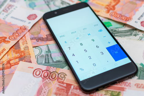 Calculator on a smartphone on the background of Russian money. Banknotes of Russia.