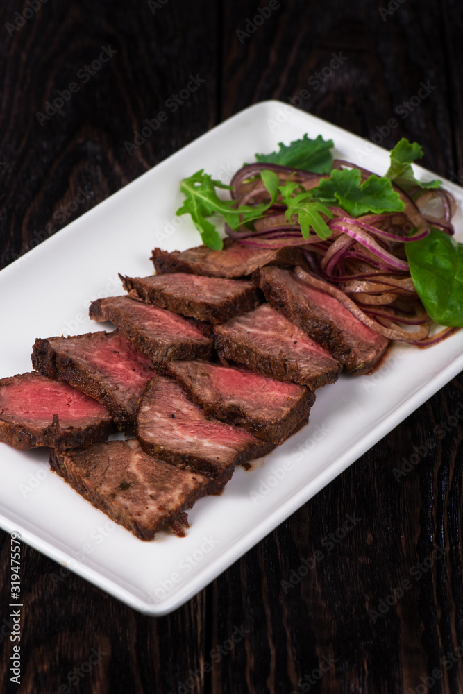 Plate with meat cutting and fresh greens on white plate