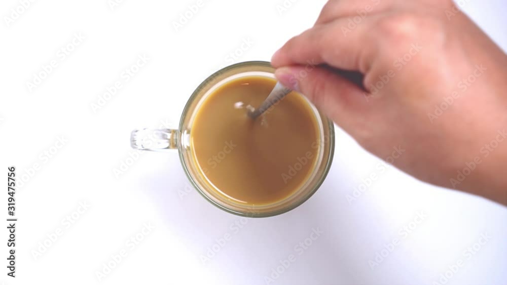Top view, person hand stirring hot milk coffee or hot milk tea with spoon on white background Top view, person hand stirring hot milk coffee or hot milk tea with spoon on white background