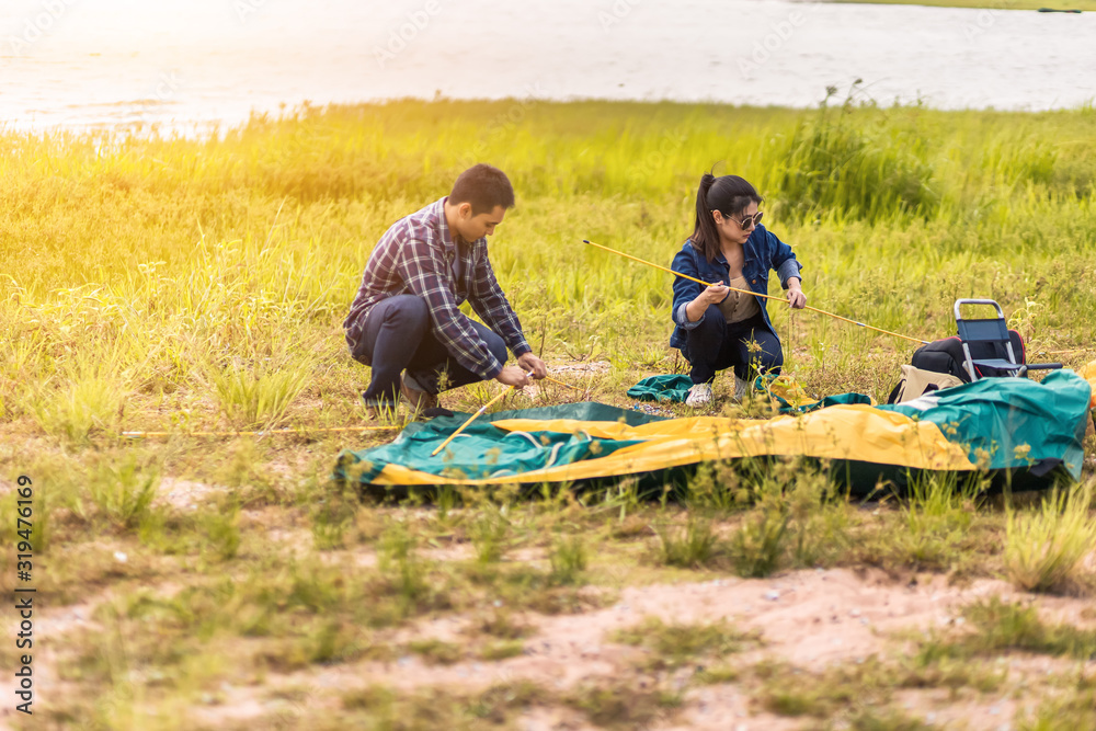 People Pitch a tent on the ground near the lake at sunset. Relaxing, traveling, long weeked, holiday concept. People Pitch a tent on the ground near the lake at sunset. Relaxing, traveling, long weeked, holiday concept.