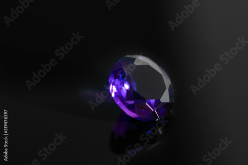 Round purple amethyst gemstone on black reflective surface