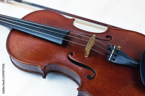 The wooden violin put on white background,in front of blurred bow,show front side of string instrument