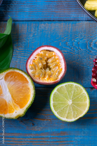 Passion fruit, tangerine and lime halves on the blue wooden table