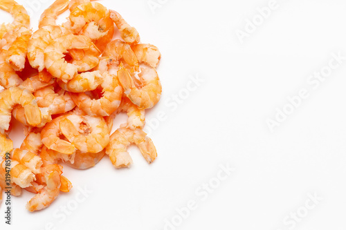 A handful of boiled peeled shrimp on a white background in the left corner