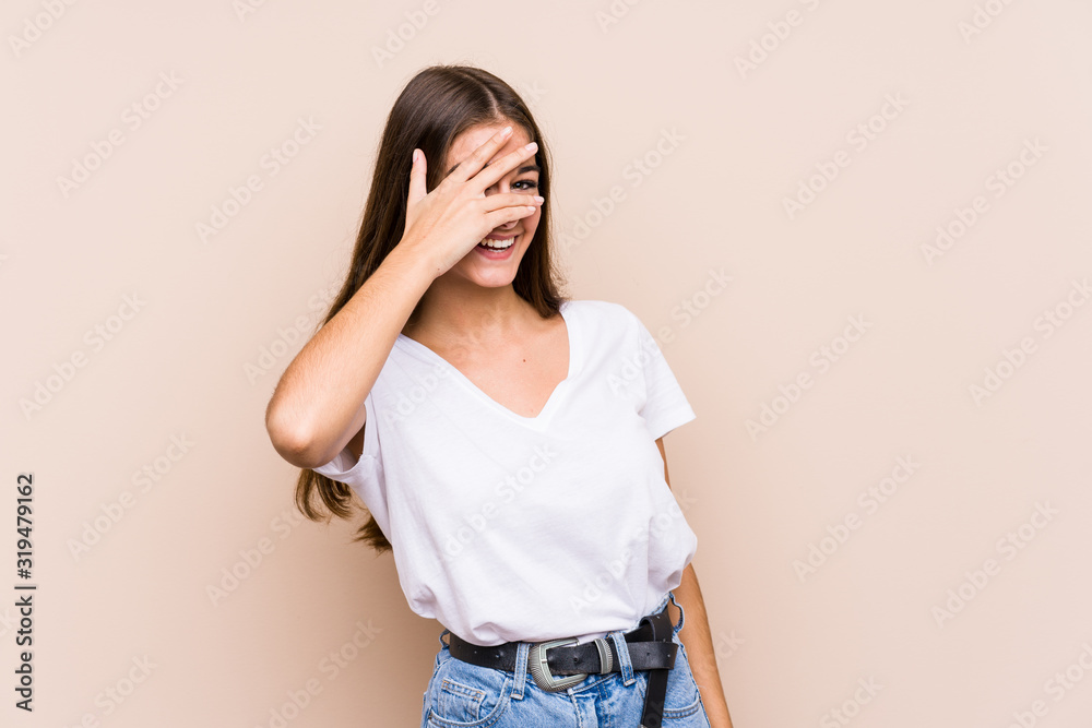 Young caucasian woman posing isolated blink at the camera through fingers, embarrassed covering face. Young caucasian woman posing isolated blink at the camera through fingers, embarrassed covering face.