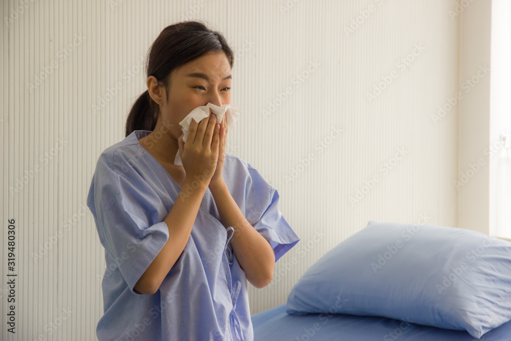 Young Asian woman is sick, has a high fever, sneezing, is recuperating in the hospital room. Young Asian woman is sick, has a high fever, sneezing, is recuperating in the hospital room.