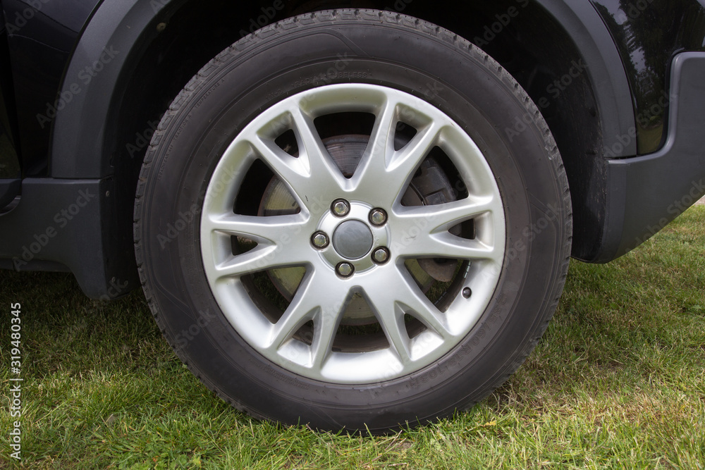 Modern unidentifiable black suv car wheel on rural roadside, closeup frontal photo