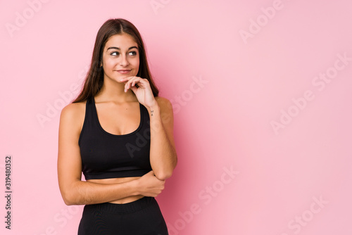 Young caucasian fitness woman doing sport isolated looking sideways with doubtful and skeptical expression.