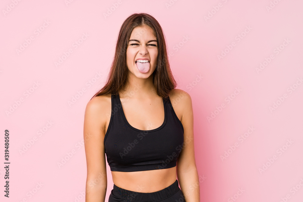 Young caucasian fitness woman doing sport isolated funny and friendly sticking out tongue. Young caucasian fitness woman doing sport isolated funny and friendly sticking out tongue.
