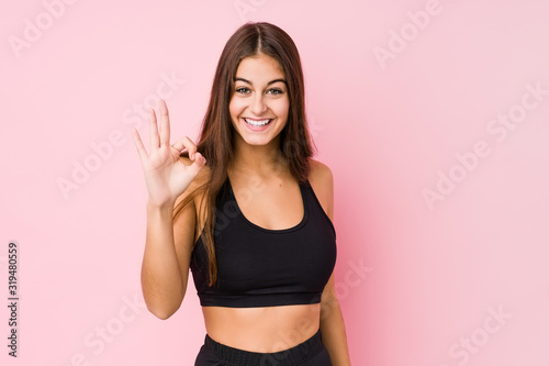 Young caucasian fitness woman doing sport isolated cheerful and confident showing ok gesture.
