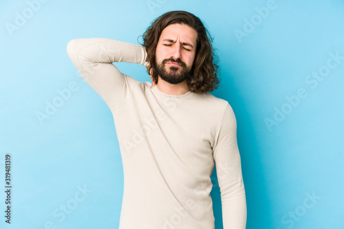 Foto Young long hair man isolated on a blue background suffering neck pain due to sedentary lifestyle