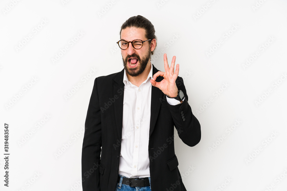 Young caucasian business man isolated on a white background winks an eye and holds an okay gesture with hand. Young caucasian business man isolated on a white background winks an eye and holds an okay gesture with hand.