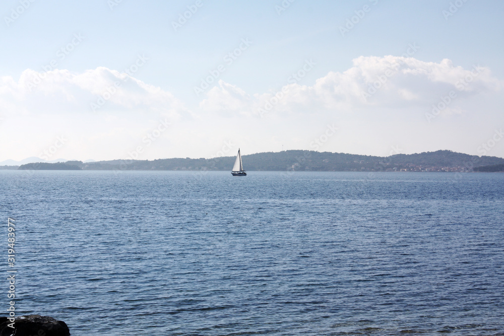 Boat with white sail in Adriatic Sea.