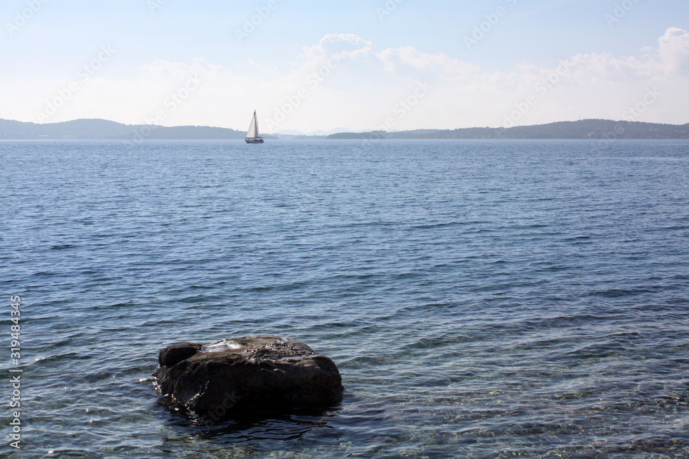 Boat with white sail in Adriatic Sea.