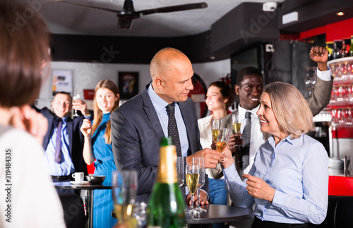 Canvas Print Cheerful middle aged woman with male colleague enjoying office party in bar, tal