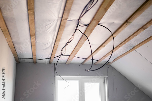 The concept of repair in a private house. Laying electrical wires on the ceiling.