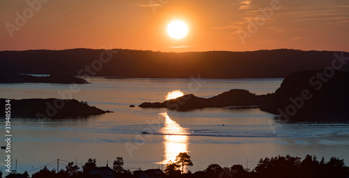 Setting sun over Archipelago of Sweden, Rörtången and big island Brattön - Low sun casts light over reflecting sea and valley. photo