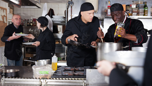 Positive cooks in process of working in kitchen of restaurant