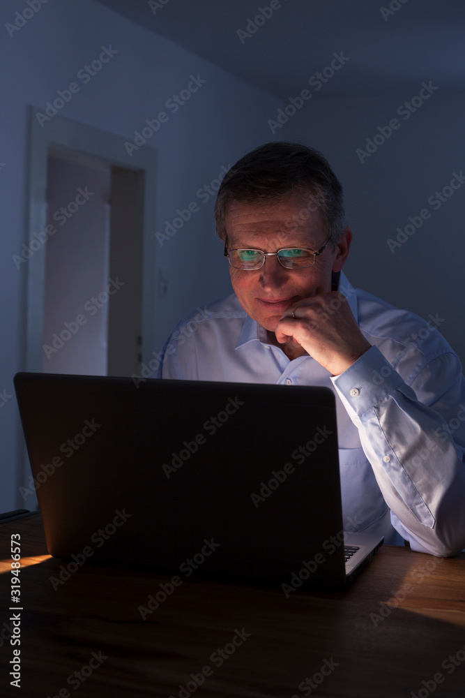 Smiling man working with laptop at night