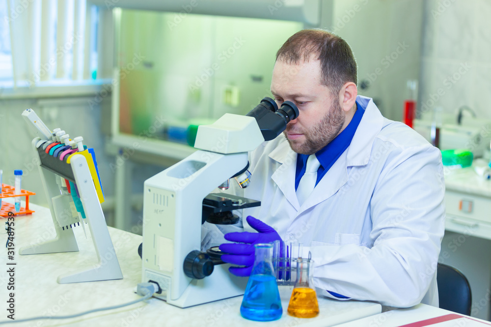 Specialist looking through microscope performing scientific research in a laboratory. Urine test. Specialist looking through microscope performing scientific research in a laboratory. Urine test.