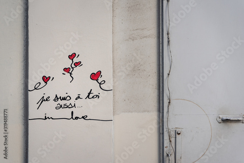 red love hearts graffitti with french writing and heartfelt messages on a tan colored wall in Montmartre, Paris