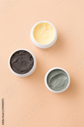 beauty, spa and wellness concept - blue clay mask, body butter and therapeutic mud on beige background