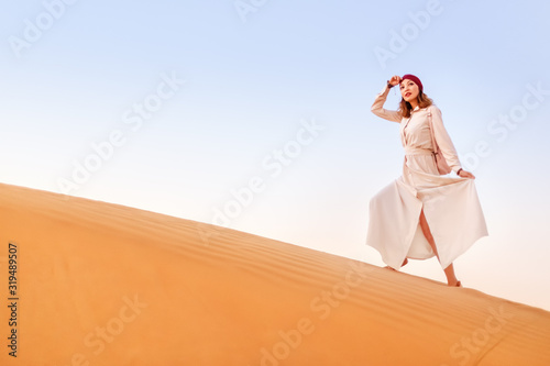Happy asian woman in turban travels in Sahara desert. Adventure and life experience concept