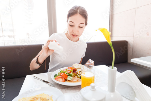 Asian woman in casual clothes having continental breakfast in hotel restaurant