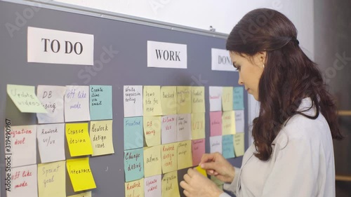 attractive scrum master putting sticky note with ui lettering on board  photo