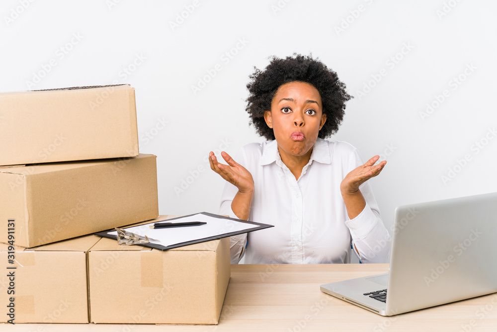 Warehouse manager sitting checking deliveries with laptop shrugs shoulders and open eyes confused. Warehouse manager sitting checking deliveries with laptop shrugs shoulders and open eyes confused.