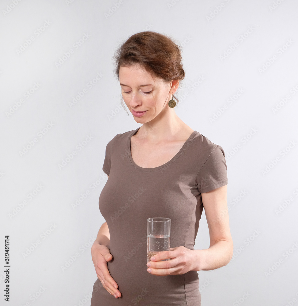 Young pregnant woman holds a glass of water Young pregnant woman holds a glass of water