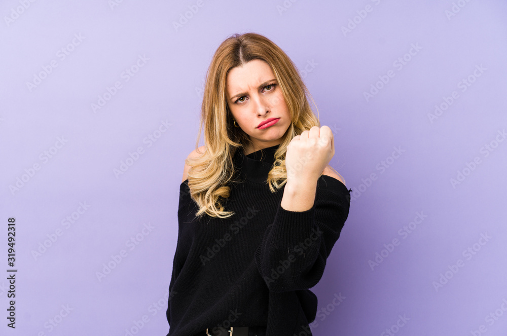 Young blonde woman isolated showing fist to camera, aggressive facial expression. Young blonde woman isolated showing fist to camera, aggressive facial expression.