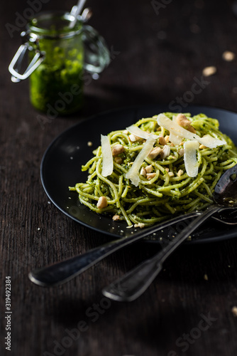 Spaghetti with basil pesto, cahews and parmesan cheese. Served on black plate. 