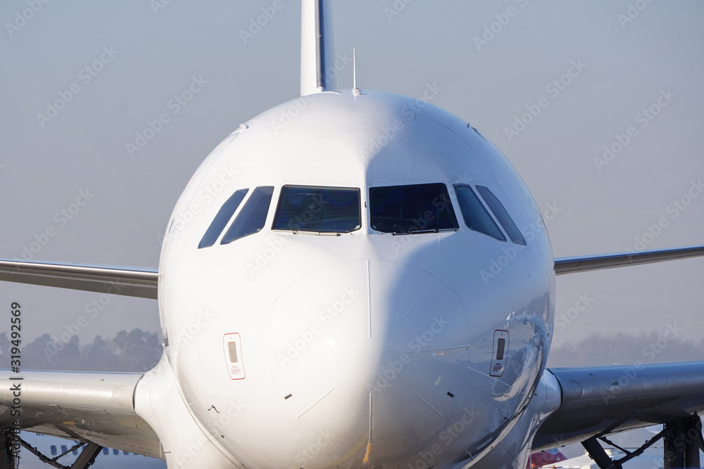 The front nose and cockpit of an Airbus A319-100 passenger plane, the cockpit glazing, blue sky in the background The front nose and cockpit of an Airbus A319-100 passenger plane, the cockpit glazing, blue sky in the background
