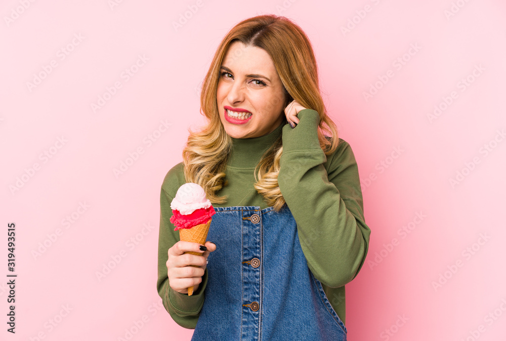 Young blonde woman eating an ice cream isolated covering ears with hands. Young blonde woman eating an ice cream isolated covering ears with hands.