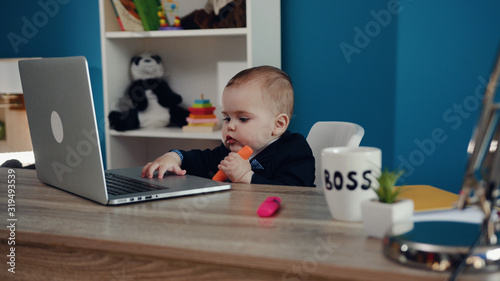 Adorable boss baby working hard by the laptop with notepad and highlighter. Cuteness, toddler boy, successful childhood. Modern office. Joke concept, happiness, playful mood photo