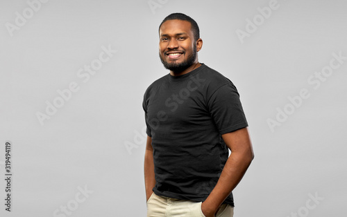 people concept - happy smiling young african american man in black t-shirt over grey background photo