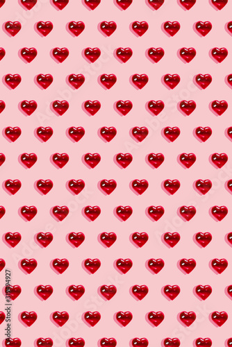Valentine's day background. Pattern of glass red hearts on a pastel pink background. Card minimalism, Symbol of love